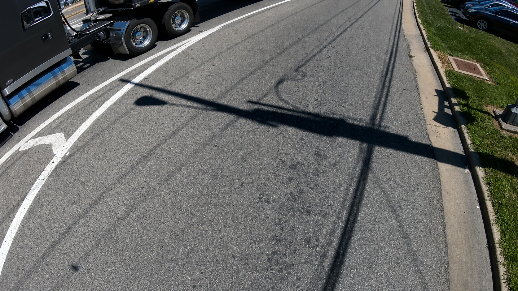 Restored and sharpened C6 rear exterior transit camera view showing the adjacent roadway, lane line, curb, and surrounding traffic.